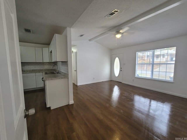 kitchen featuring a textured ceiling, sink, white cabinets, vaulted ceiling with beams, and dark hardwood / wood-style floors