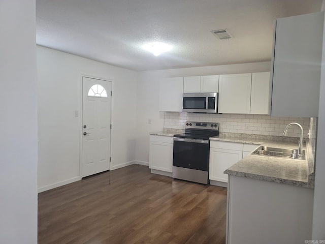 kitchen with white cabinets, sink, dark hardwood / wood-style floors, decorative backsplash, and stainless steel appliances