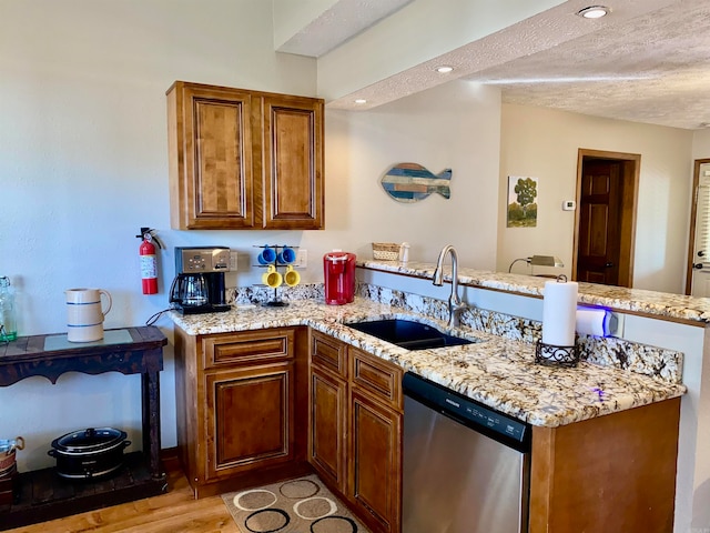 kitchen with dishwasher, sink, light wood-type flooring, a textured ceiling, and kitchen peninsula