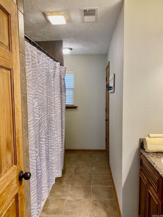 bathroom with tile patterned flooring, vanity, a textured ceiling, and a shower with shower curtain