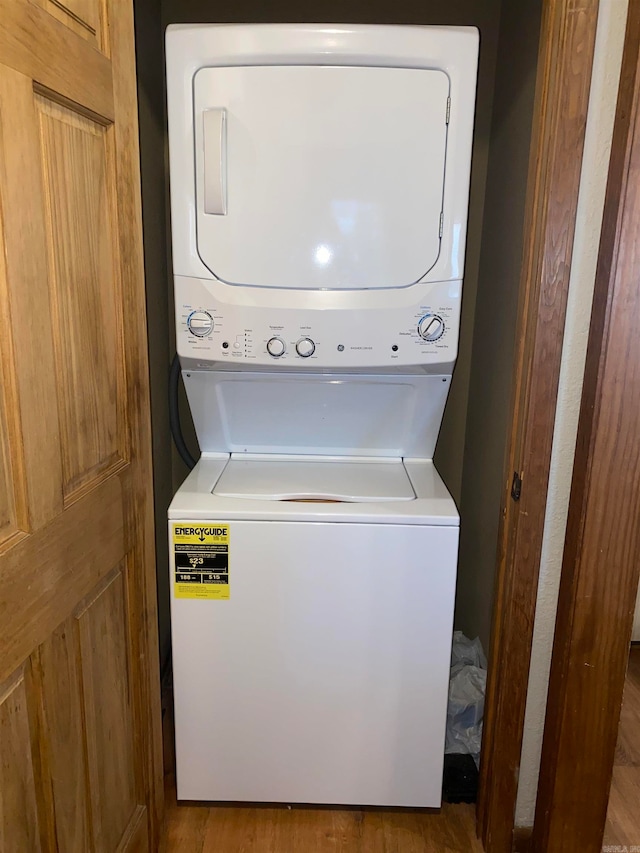 laundry area with hardwood / wood-style flooring and stacked washer / drying machine