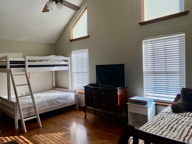 bedroom with ceiling fan, dark hardwood / wood-style floors, high vaulted ceiling, and multiple windows