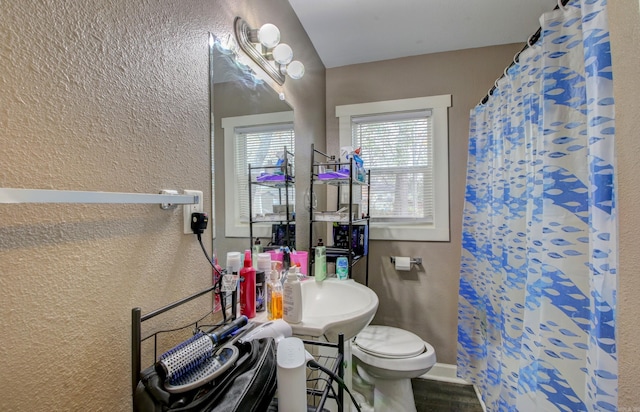 bathroom with sink, a shower with shower curtain, and toilet