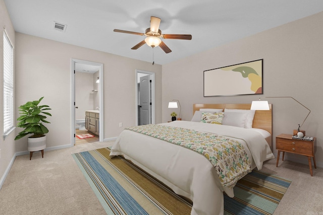 bedroom featuring multiple windows, light carpet, ensuite bathroom, and ceiling fan