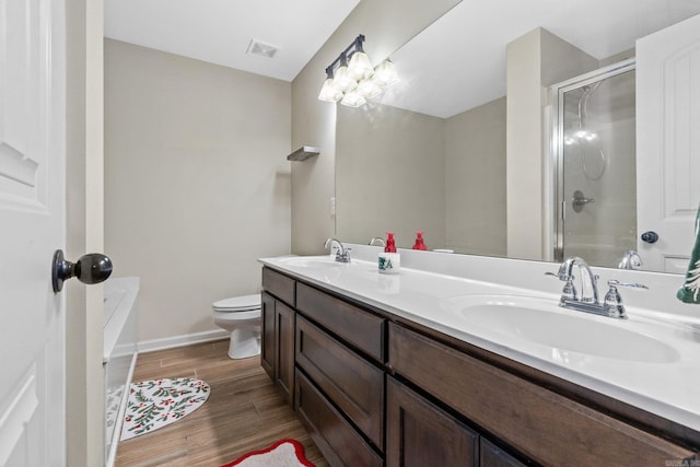 bathroom featuring vanity, hardwood / wood-style flooring, toilet, and a shower with door