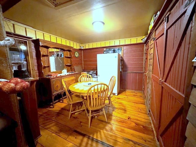 dining room featuring light wood-type flooring and wood walls