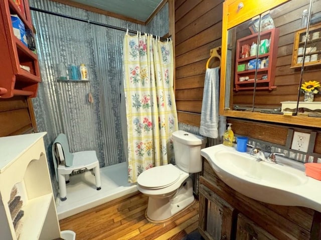 bathroom with a shower with shower curtain, vanity, hardwood / wood-style flooring, toilet, and wood walls