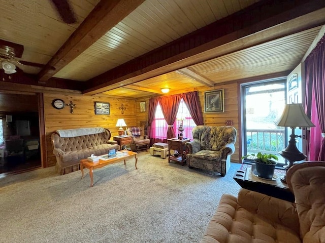 carpeted living room with beamed ceiling, wood ceiling, ceiling fan, and wood walls