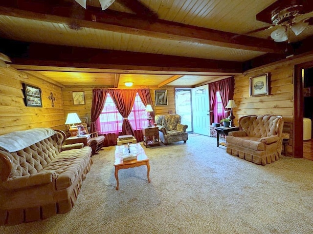 living room featuring ceiling fan, beamed ceiling, carpet floors, wooden walls, and wood ceiling