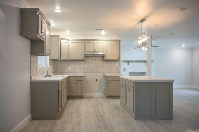 kitchen with gray cabinetry, sink, hanging light fixtures, light hardwood / wood-style flooring, and backsplash