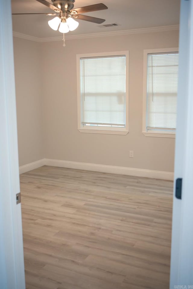 empty room with ceiling fan, ornamental molding, and light wood-type flooring