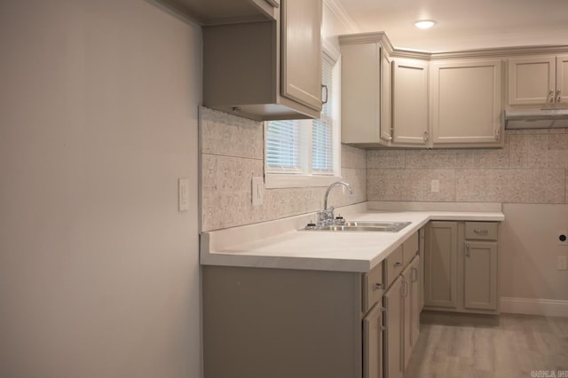 kitchen with backsplash, sink, light hardwood / wood-style flooring, gray cabinets, and ornamental molding