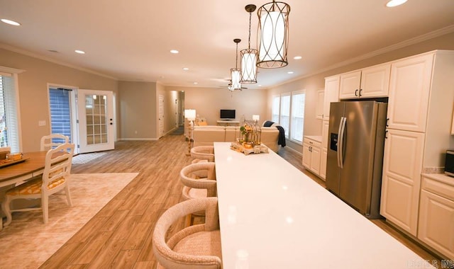 kitchen featuring white cabinetry, hanging light fixtures, crown molding, appliances with stainless steel finishes, and light wood-type flooring