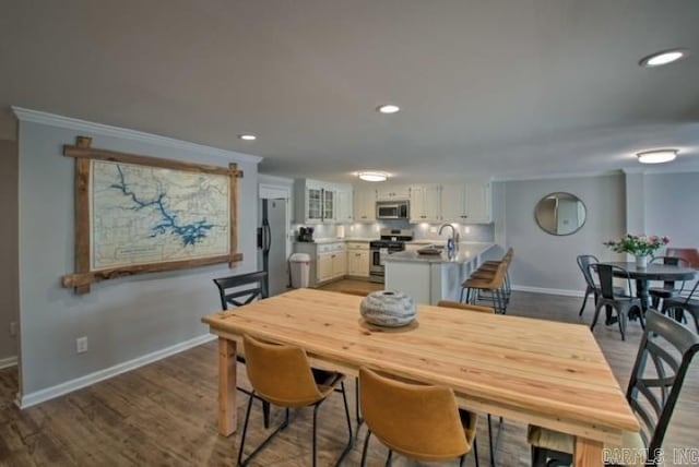 dining area with dark hardwood / wood-style floors, ornamental molding, and sink
