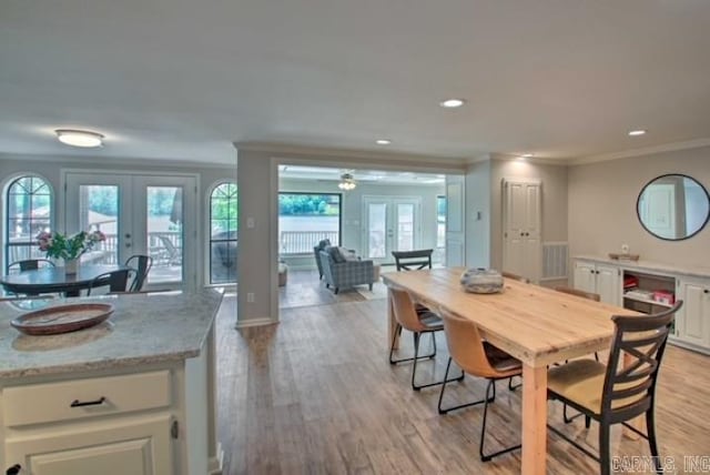 dining space with plenty of natural light, ornamental molding, light hardwood / wood-style flooring, and french doors