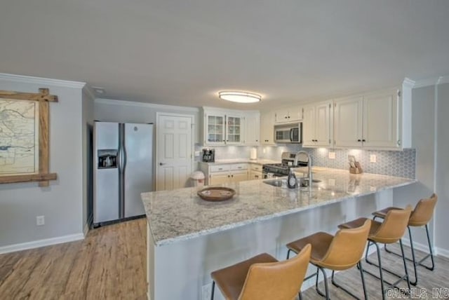 kitchen featuring light stone countertops, appliances with stainless steel finishes, light wood-type flooring, sink, and white cabinets
