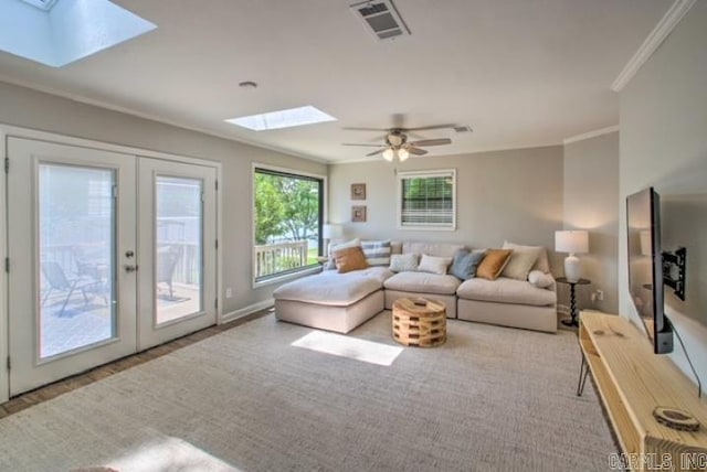 carpeted living room with a skylight, ceiling fan, french doors, and ornamental molding