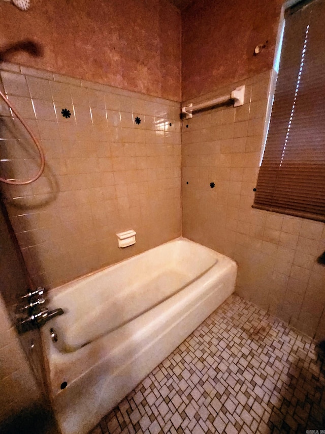 bathroom with tiled shower / bath combo and tile walls