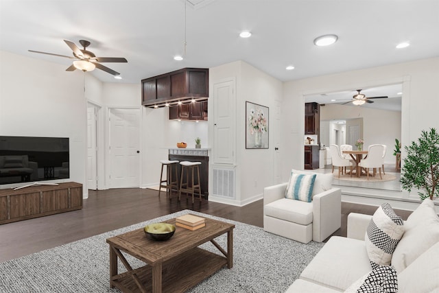 living room with ceiling fan and dark wood-type flooring