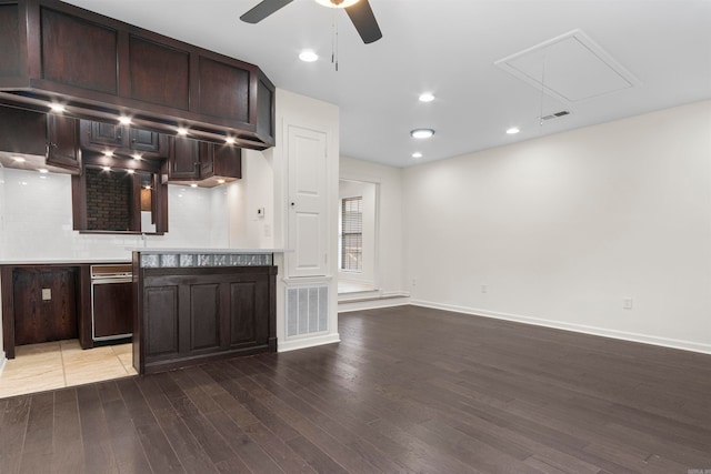 bar featuring backsplash, ceiling fan, dark brown cabinets, and hardwood / wood-style flooring