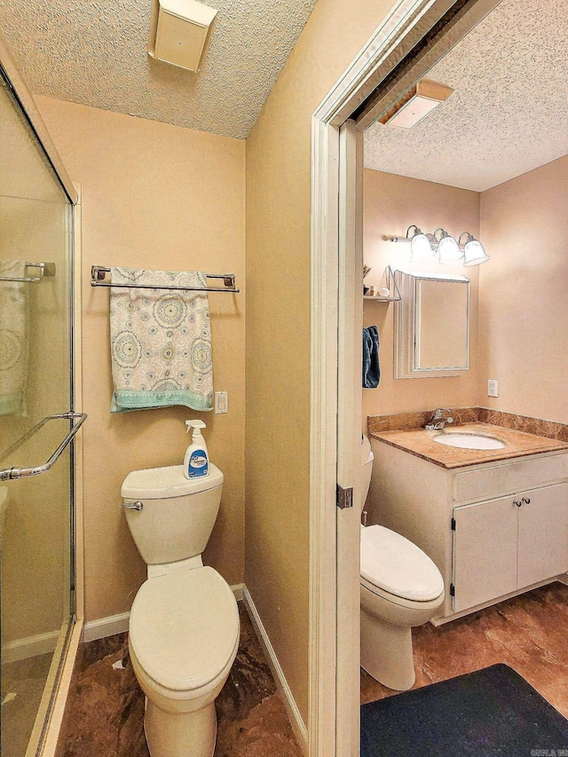 bathroom featuring a shower with door, vanity, a textured ceiling, and toilet