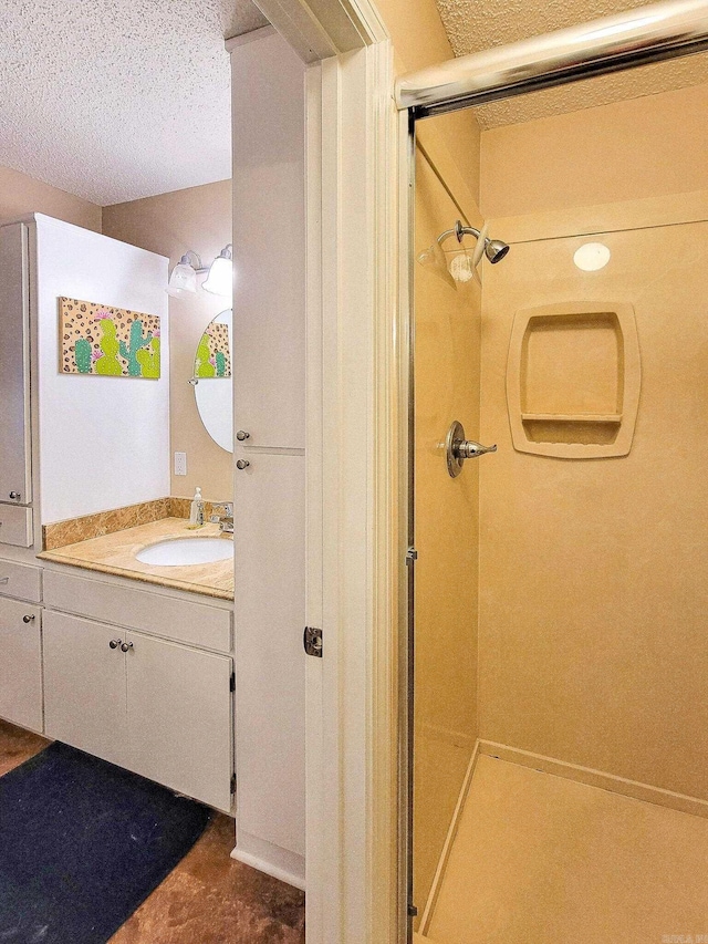 bathroom with vanity, a shower with shower door, and a textured ceiling