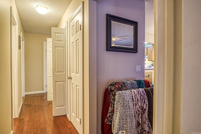 hall with wood-type flooring and a textured ceiling