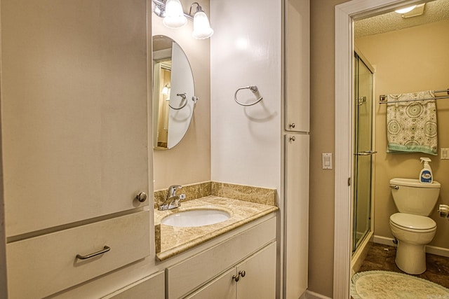 bathroom with vanity, toilet, a shower with door, and a textured ceiling