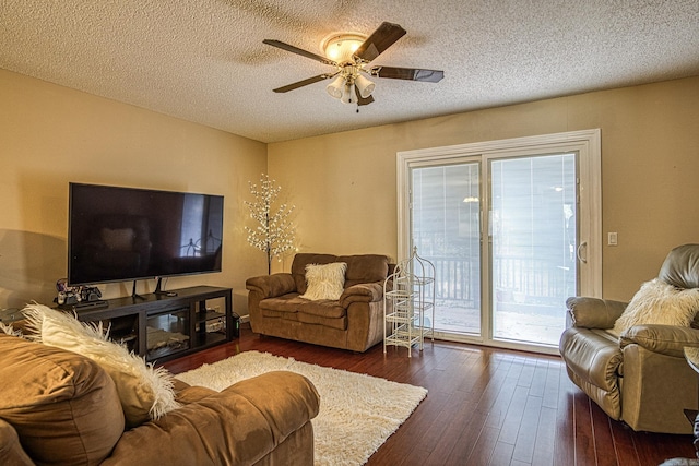 living room with a textured ceiling, ceiling fan, and dark wood-type flooring