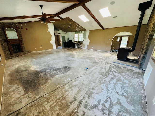 unfurnished living room with beamed ceiling, plenty of natural light, and ceiling fan