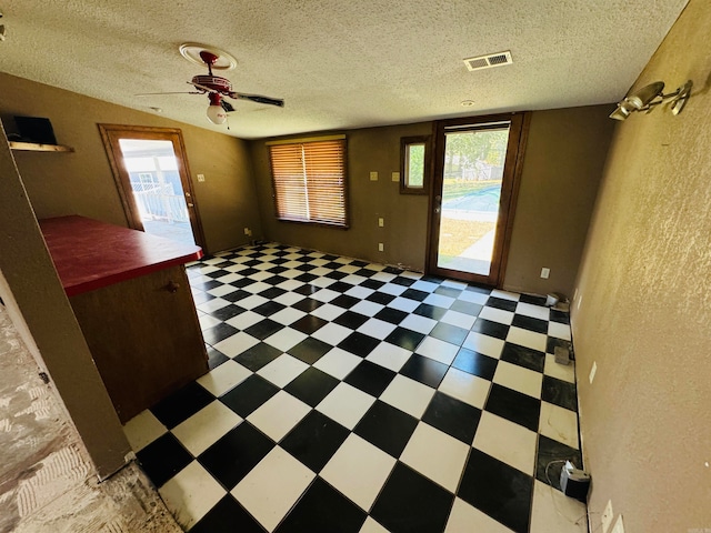 empty room with ceiling fan and a textured ceiling