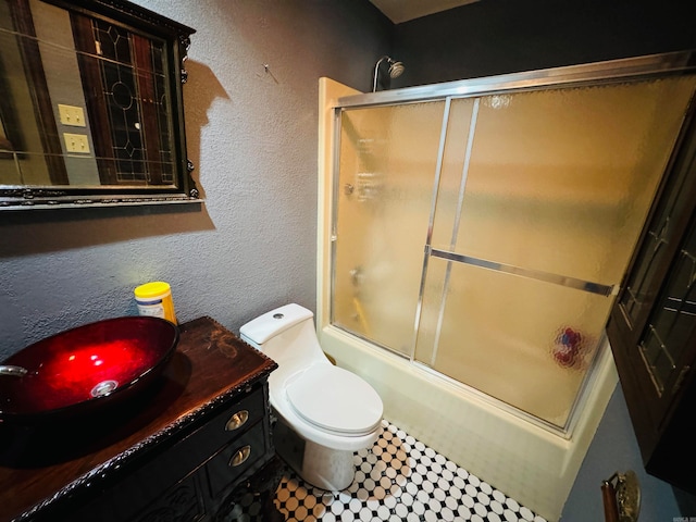 full bathroom featuring vanity, toilet, and bath / shower combo with glass door