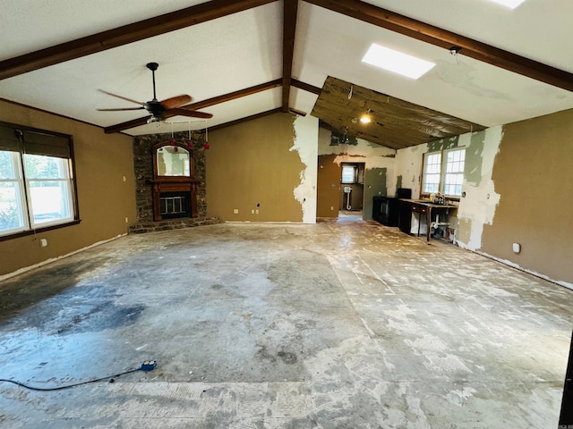 unfurnished living room with vaulted ceiling with beams, ceiling fan, and a fireplace