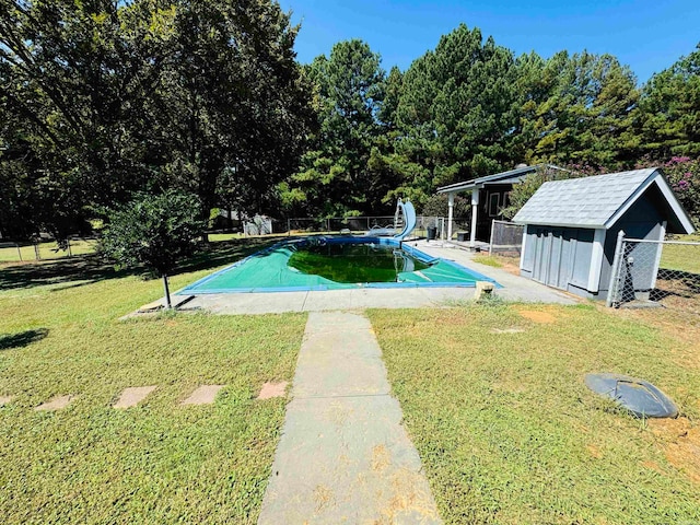 view of pool featuring a storage unit, a yard, and a water slide