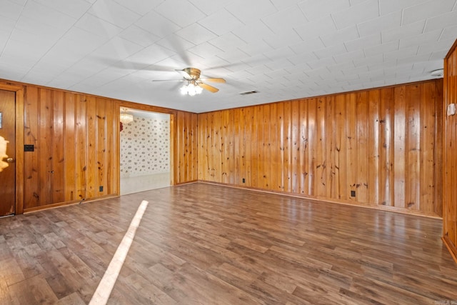 spare room with hardwood / wood-style flooring, ceiling fan, and wood walls