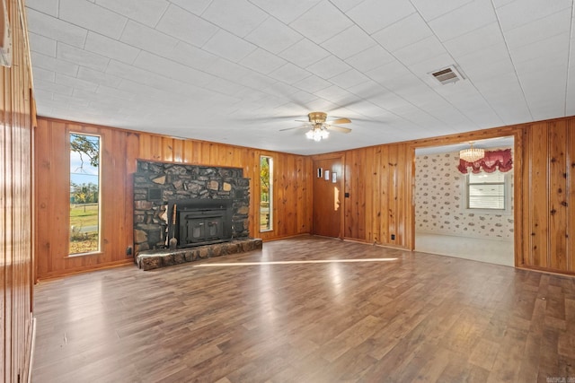 unfurnished living room featuring hardwood / wood-style floors, ceiling fan, and wooden walls