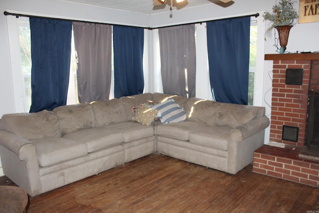 living room featuring ceiling fan, dark hardwood / wood-style floors, and a brick fireplace