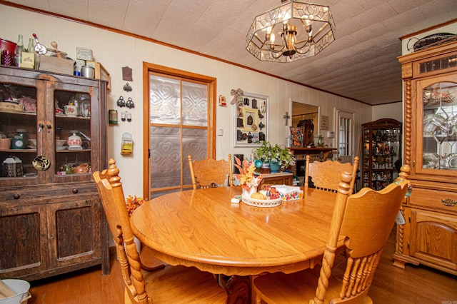 dining area with crown molding, hardwood / wood-style floors, and a notable chandelier