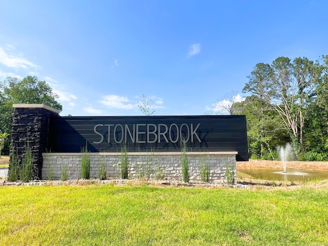 community / neighborhood sign with a lawn and a water view