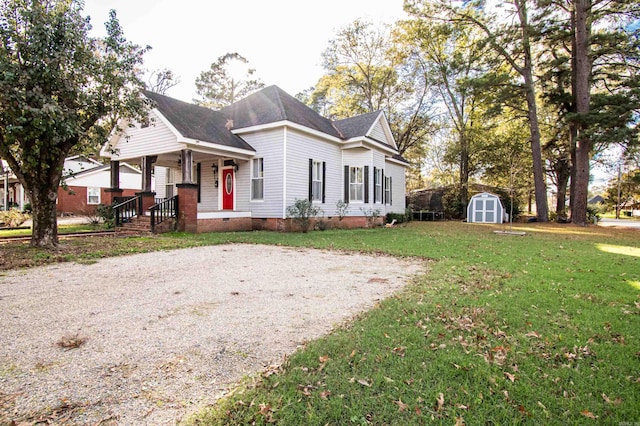 view of front of home featuring covered porch, a shed, and a front lawn