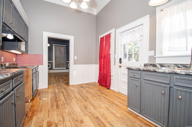 kitchen with gray cabinetry, light wood-type flooring, crown molding, and tasteful backsplash