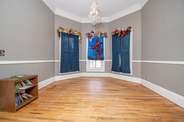 spare room featuring a chandelier, light hardwood / wood-style flooring, and crown molding