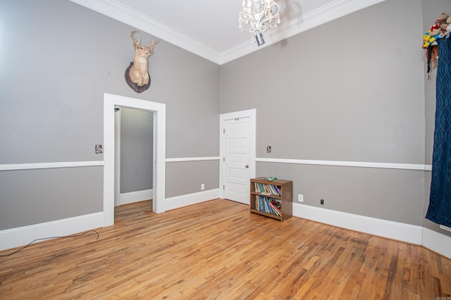 spare room featuring hardwood / wood-style floors, a notable chandelier, ornamental molding, and a high ceiling