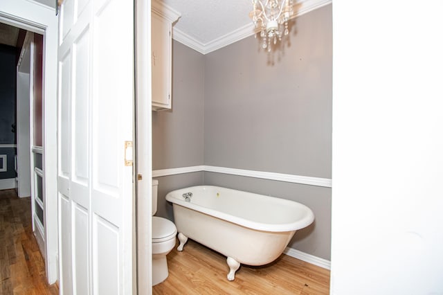 bathroom featuring a bathtub, ornamental molding, a textured ceiling, hardwood / wood-style floors, and toilet