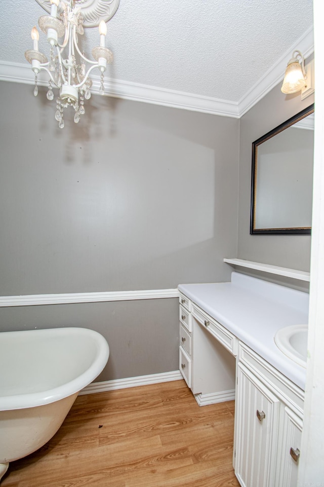 bathroom featuring a textured ceiling, vanity, wood-type flooring, and ornamental molding