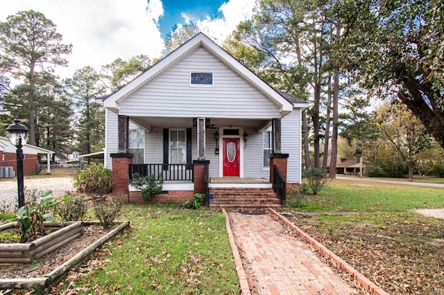 bungalow-style house featuring central AC unit, a porch, and a front yard