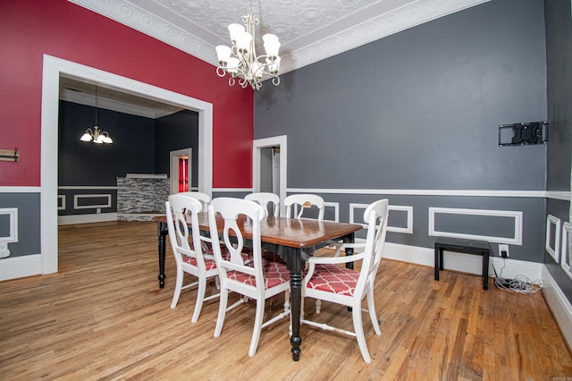 dining room with hardwood / wood-style floors, a notable chandelier, ornamental molding, and a textured ceiling