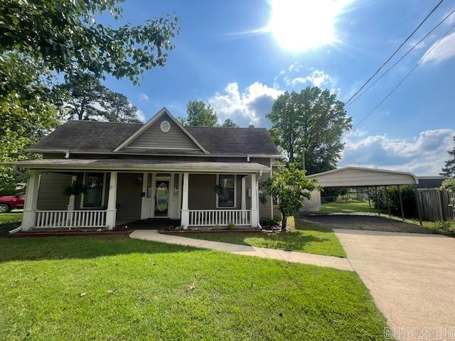 1905 Bethesda, Mena, AR 71953 - view of front of house featuring a porch, driveway, a detached carport, and a front lawn