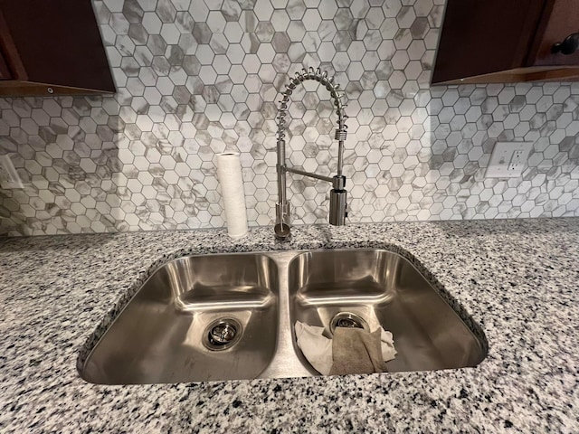 details featuring light stone countertops, a sink, decorative backsplash, and dark brown cabinets