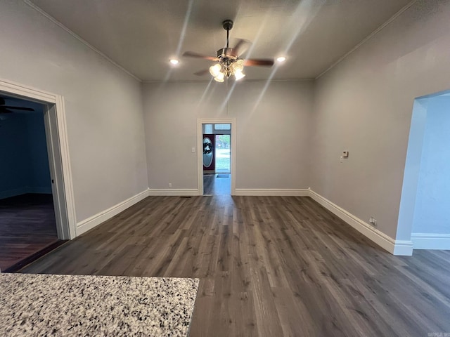 spare room with dark wood-type flooring, baseboards, and a ceiling fan